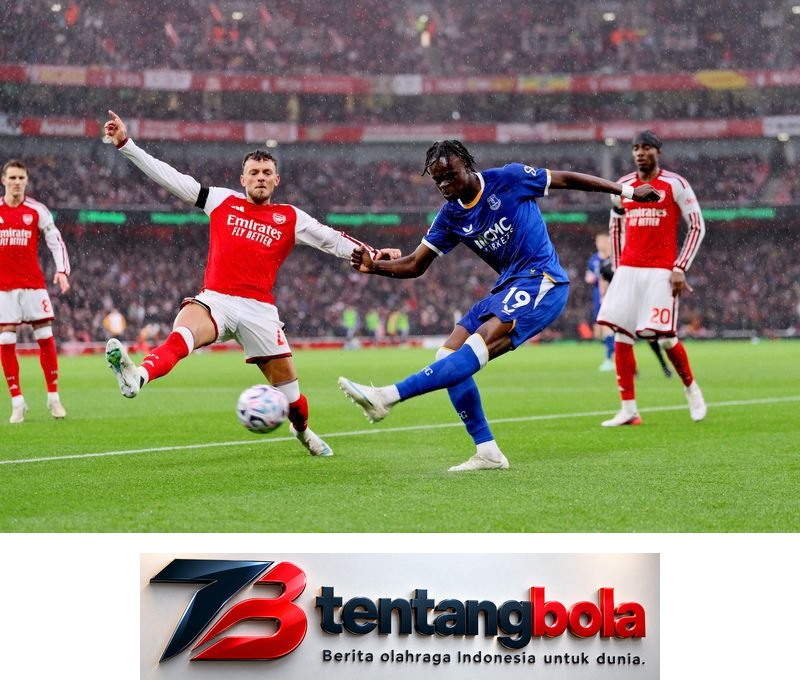 Pemain Everton berseragam biru menendang bola di antara pemain Arsenal.